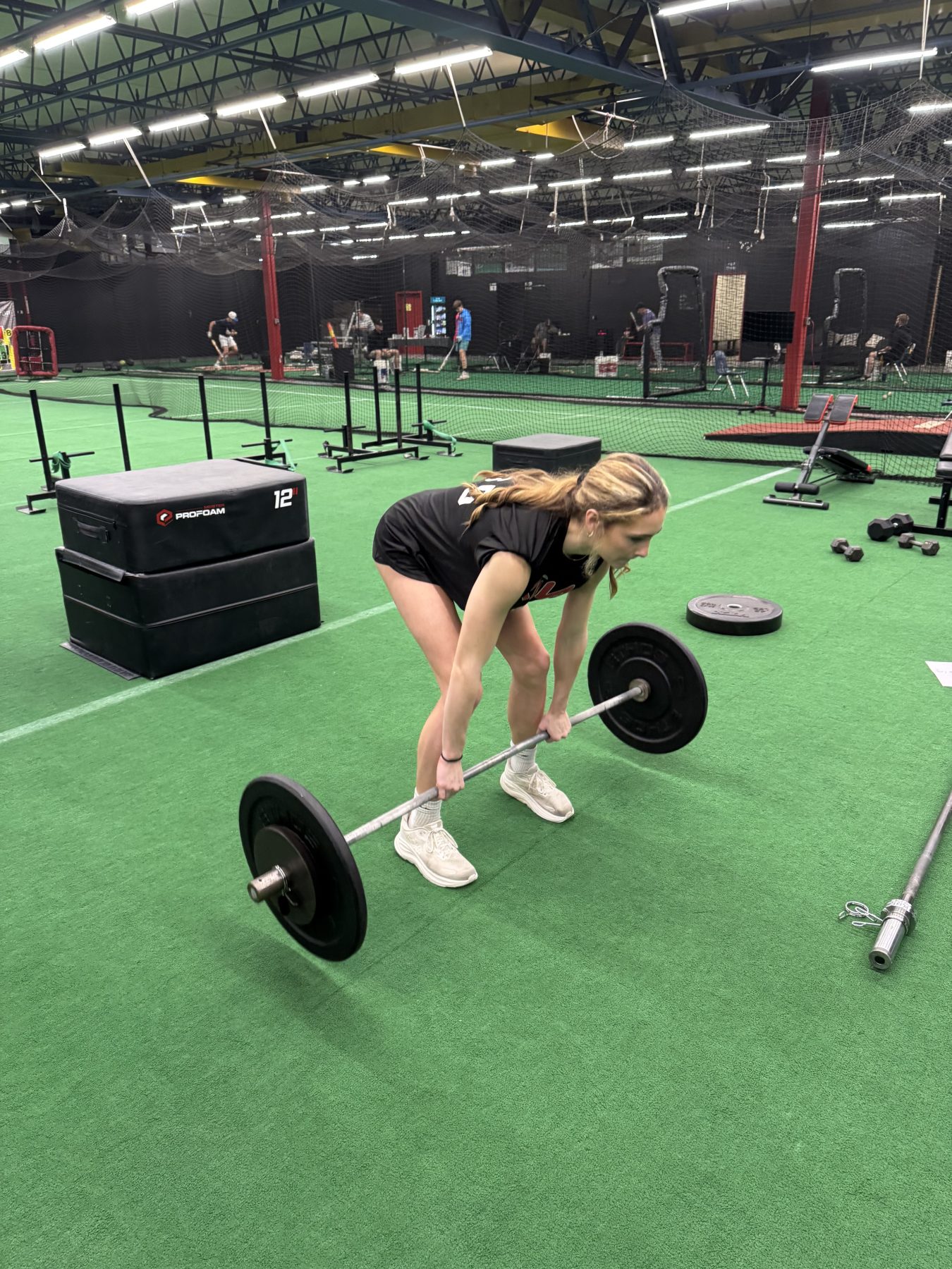 Athlete training on turf beside batting cages